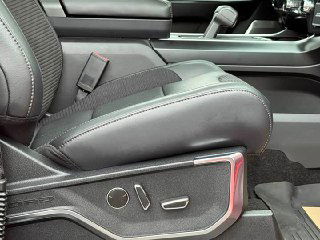 Переднее кресло Ford F-150 Raptor крупным планом: регулируемые электрические органы, кожаная обивка и декоративные строчки на сиденье.