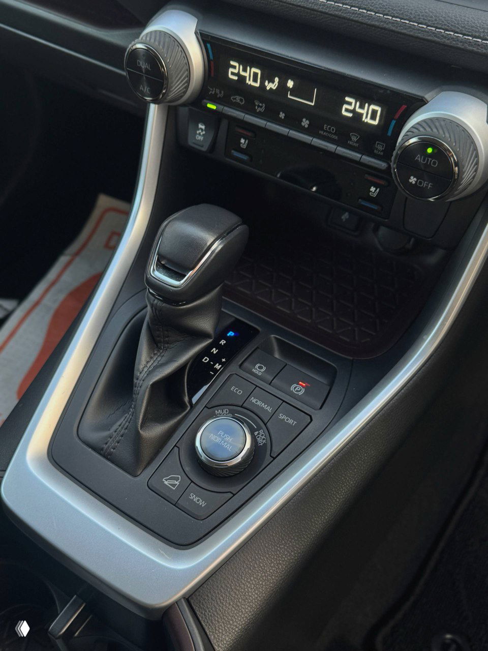Крупный план центральной консоли Toyota RAV4: рычаг вариатора, регуляторы режимов движения (ECO, NORMAL, SPORT) и селектор режимов привода, чистая заводская отделка салона.