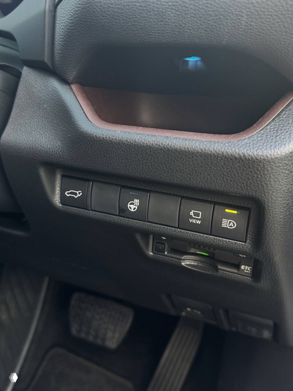 Панель с кнопками у водителя: открытие багажника, подогрев руля, кнопка VIEW и индикатор системы автостарт-стоп — вид внизу от рулевой колонки на блок переключателей.