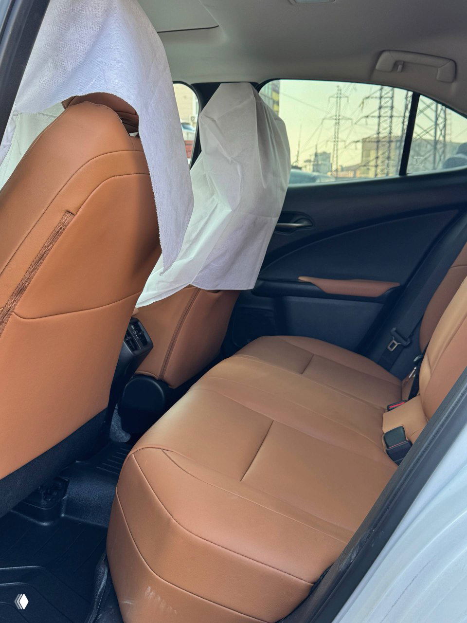 Задний ряд сидений с коричневой кожаной обивкой в Lexus UX200; виден запас места и состояние обивки и подголовников.