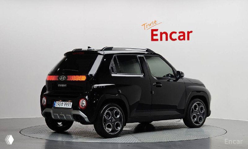 Hyundai Casper чёрного цвета, задний трёхчетвертной вид автомобиля в шоуруме, видны фонари, бампер и профиль компактного кроссовера.