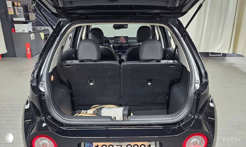 Открытый багажник Hyundai Casper со сложенными сиденьями, видна вместимость и грузовая зона на снимке из демонстрационного зала.