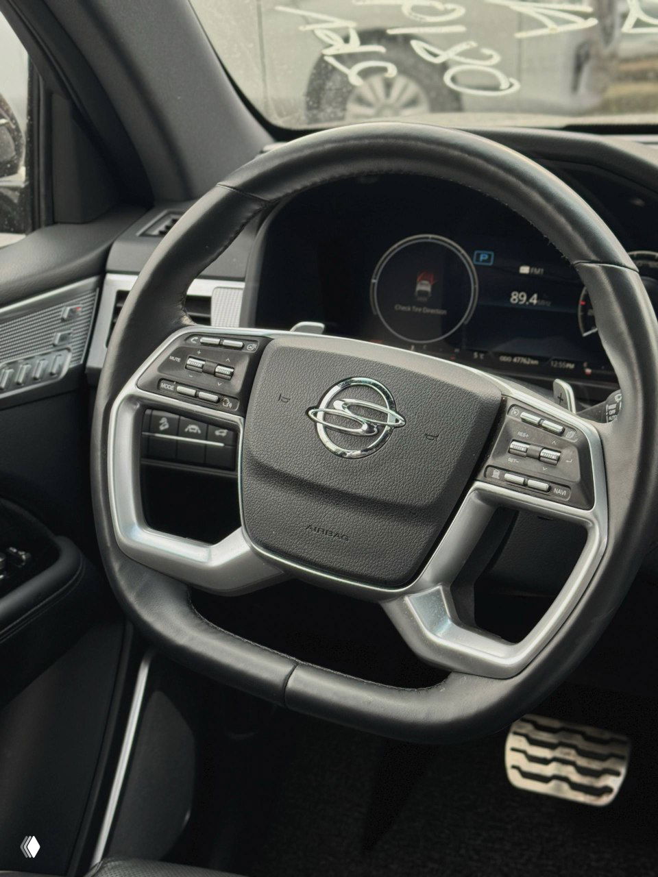 Руль SsangYong NEW Rexton с фирменным шильдом и кнопками управления: мультируль на фоне цифровой приборной панели.