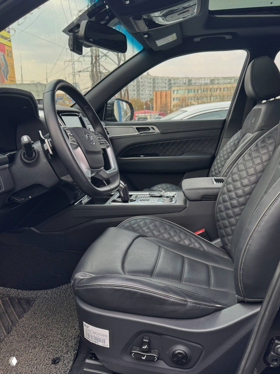 Переднее сиденье водителя SsangYong NEW Rexton: чёрная кожаная обивка с прострочкой, подлокотник и элементы регулировки сиденья.