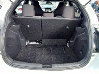 Багажник Toyota Yaris 2021 — открытый объём, чистая обивка и вид на складывающиеся спинки задних сидений; общий вид грузового отделения.