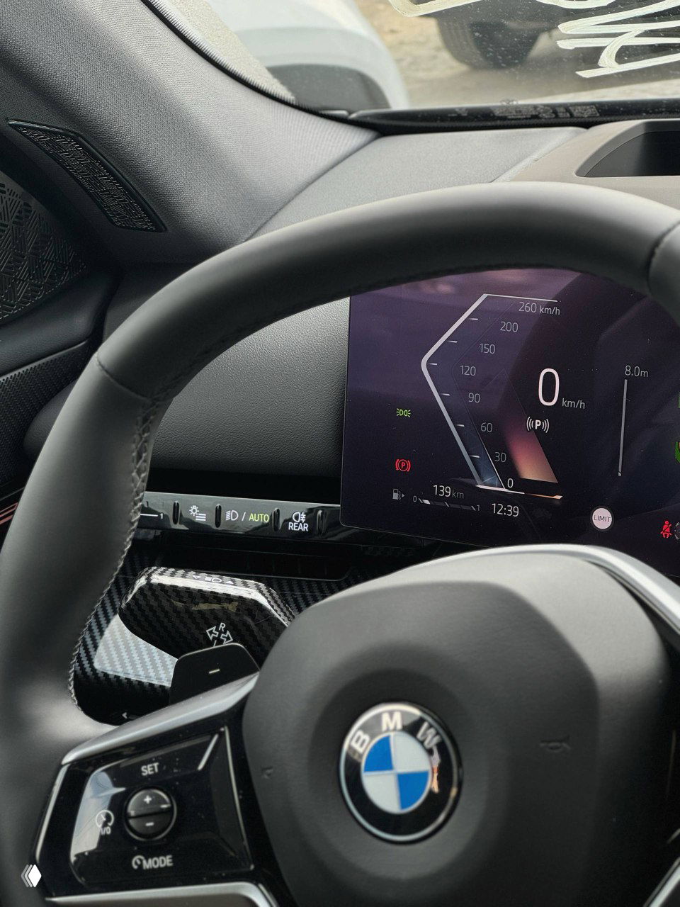 Крупный план руля и цифрового дисплея BMW, приборная панель показывает 0 км/ч, детали интерьера и декоративные вставки.