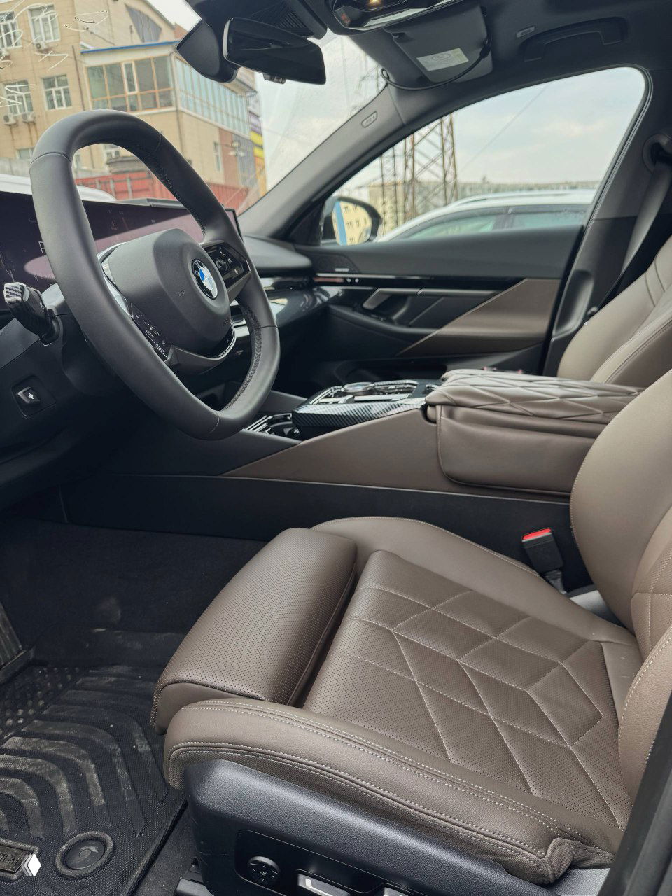 Вид салона BMW: переднее пассажирское кресло в коричневой коже, центральная консоль и общий интерьер с открытым панорамным небом.