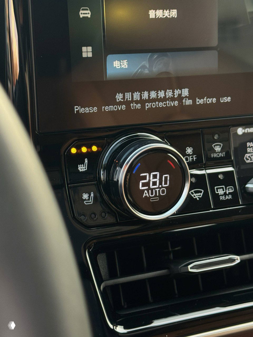 Крупный план климат-контроля и цифрового регулятора температуры в Toyota Highlander 2025 с надписью о необходимости удаления защитной плёнки на экране