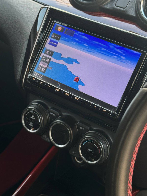 Мультимедийный экран Suzuki Swift с картой на дисплее и блоком климат-контроля под ним, крупный план панели управления и кнопок.