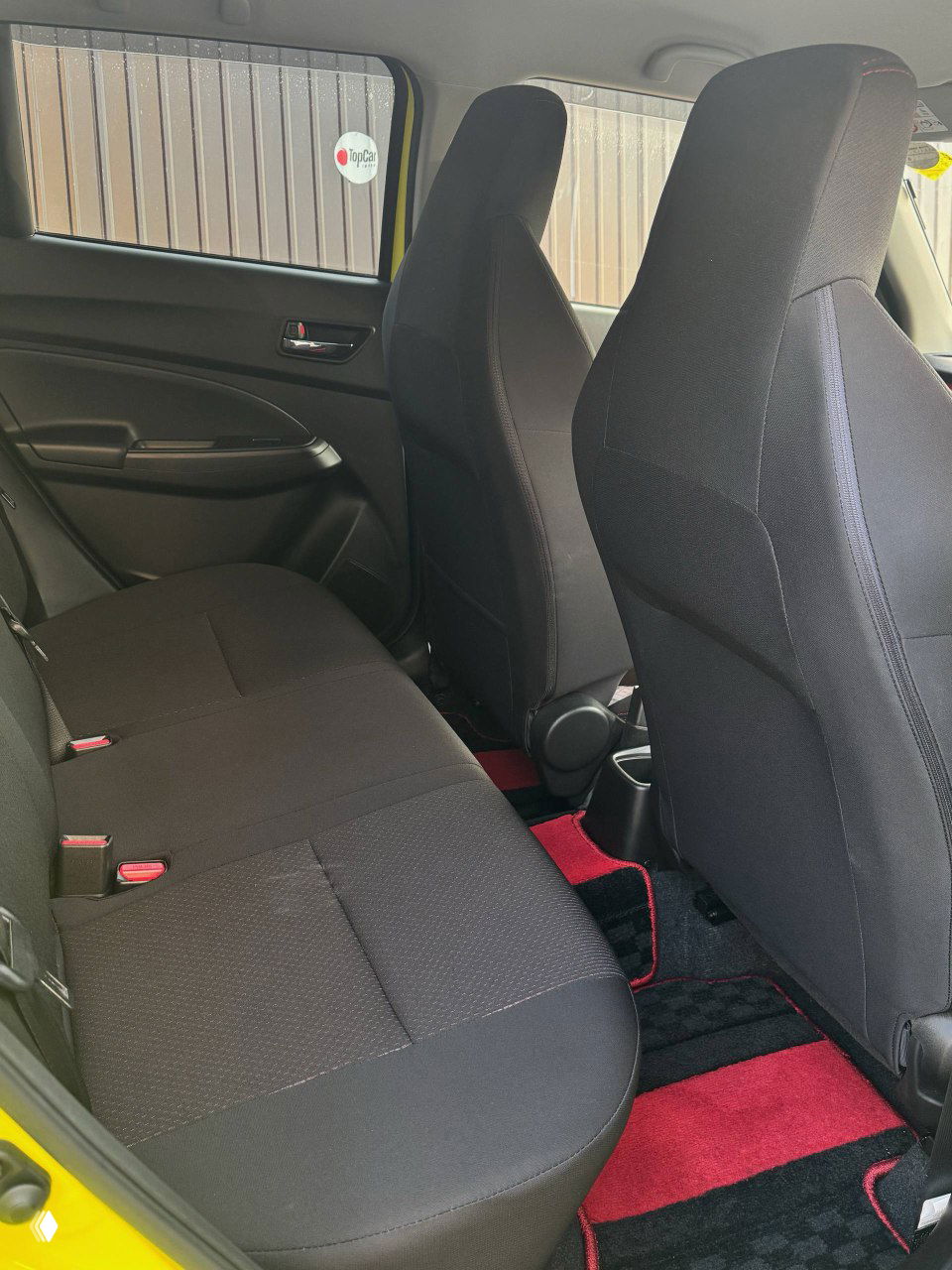 Задний диван Suzuki Swift, общий вид на салон сзади, состояние обивки и коврики, обзор пространства для ног и посадочных мест.
