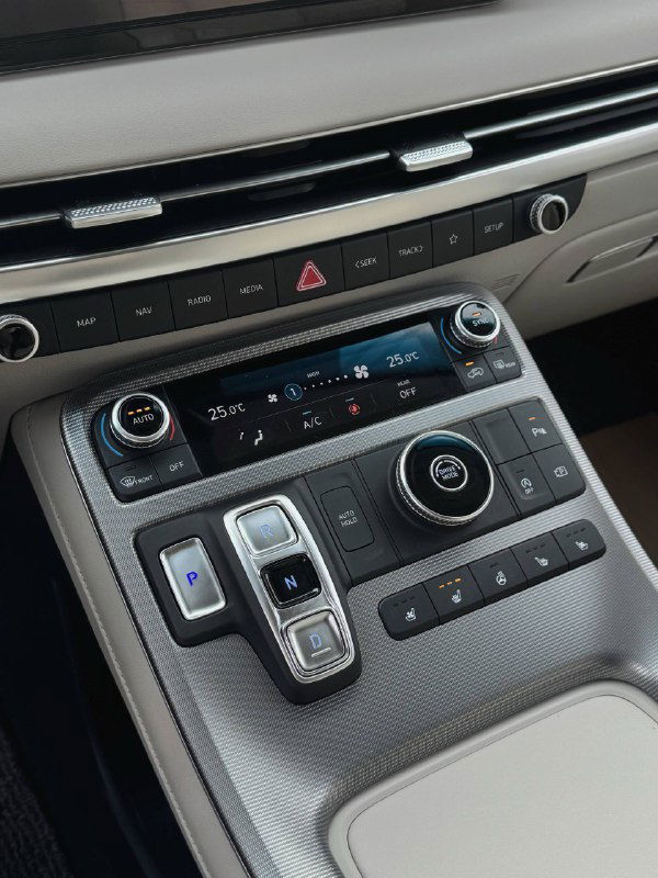 Крупный план центрального тоннеля Hyundai Palisade с кнопками селектора передач P, R, N, D, регулятора мультимедиа и панели управления климат-контролем.