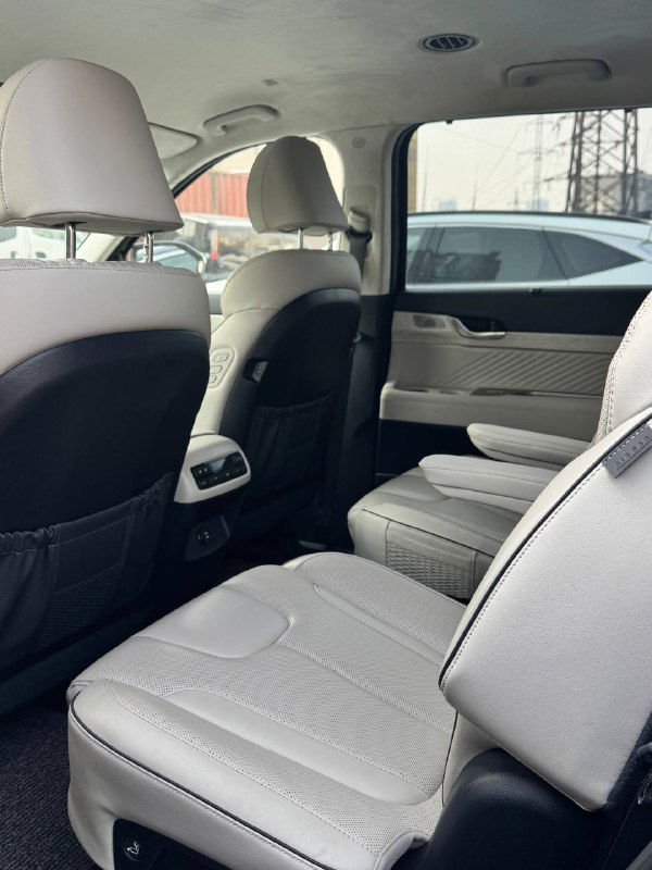 Второй ряд сидений Hyundai Palisade в светлой кожаной обивке, отдельные кресла с подлокотниками и пространство для пассажиров, фото демонстрирует состояние салона.