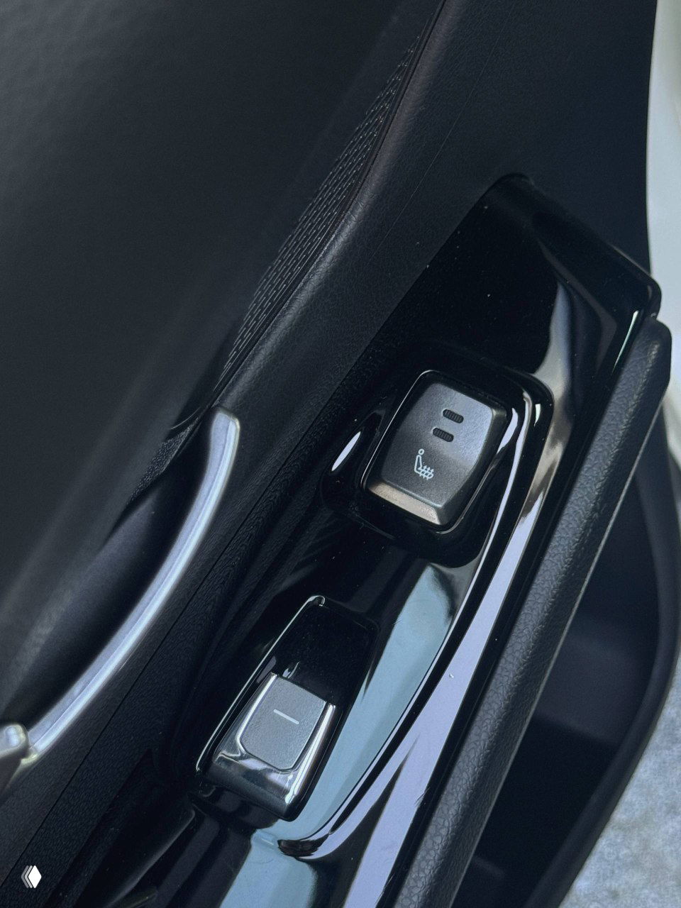 Крупный план элемента управления обогревом сидений и кнопки стеклоподъёмника на дверной панели, чёрная лакированная отделка.