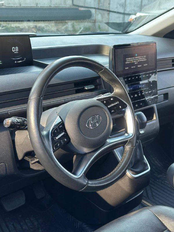 Интерьер Hyundai Staria: крупный план рулевого колеса, центральной консоли и мультимедийного экрана, показан общий вид приборной панели салона.