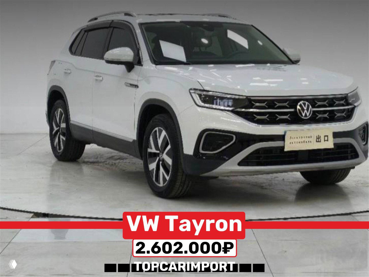 Белый Volkswagen Tayron на площадке осмотра, передний ракурс под углом, видна подпись цены 2.602.000₽ и складские стенды позади.
