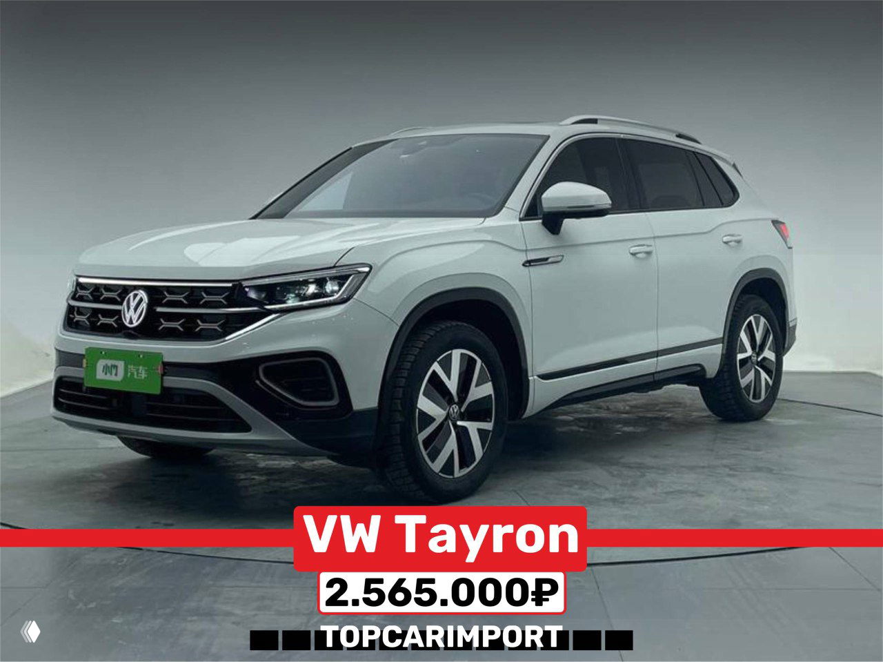 Белый Volkswagen Tayron, боковой фронтальный ракурс в шоуруме, хорошо видны колёса и профиль автомобиля, подпись цены 2.565.000₽.