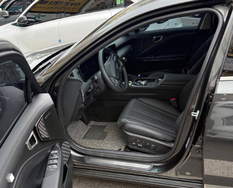 Интерьер Kia K8 Noblesse: открытая передняя дверь, кожаное сиденье водителя, панель управления и порог с накладками, вид сбоку.