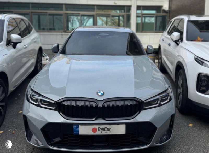 Серый BMW 320d M‑Sport, фронтальный вид на парковке с номерной рамкой TopCar; видны спортивная решётка радиатора и агрессивный передний бампер.