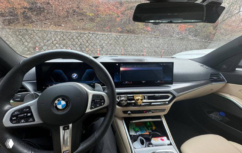 Салон BMW 320d M‑Sport: вид на руль, приборную панель и широкую мультимедиасистему; центральный тоннель и элементы отделки в кадре.