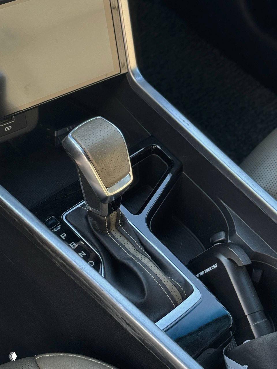 Селектор АКПП SsangYong Torres: крупный рычаг переключения передач, окантовка, кожаная прострочка и отделение для мелочей рядом с рычагом.