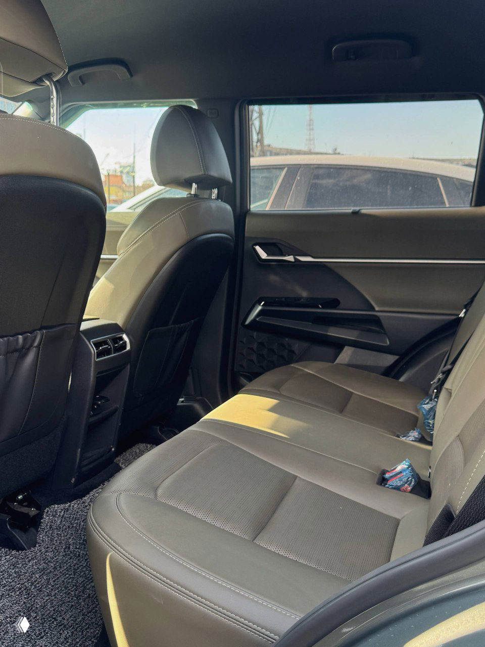 Задний ряд сидений SsangYong Torres: трёхместный диван, вентиляционные дефлекторы для задних пассажиров и простор для ног, вид сбоку через передний ряд.