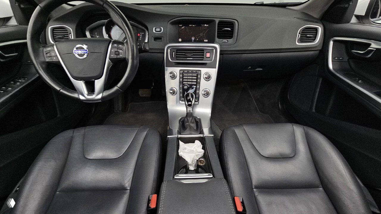 Салон Volvo S60: вид на передние сиденья, рулевое колесо и центральную консоль с экраном мультимедиа, кожаная обивка.