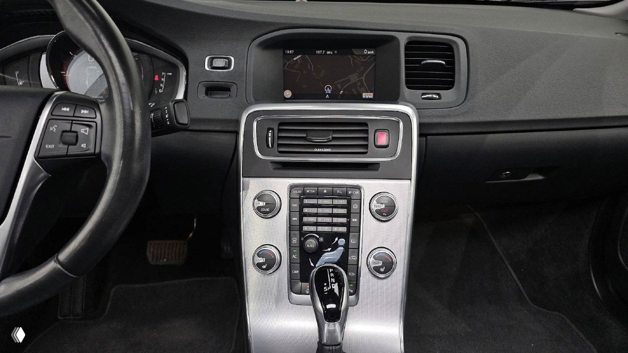 Вид центральной консоли Volvo S60 с мультимедийным экраном и рядом кнопок, фото демонстрирует состояние передней панели и экрана.