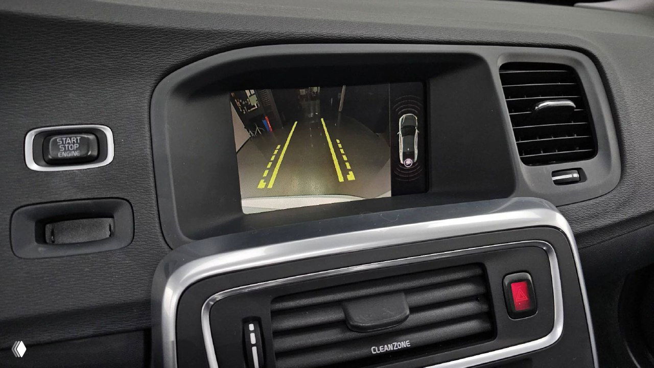 Экран парковочной камеры и часть приборной панели Volvo S60, видна индикация парковочной разметки на дисплее.