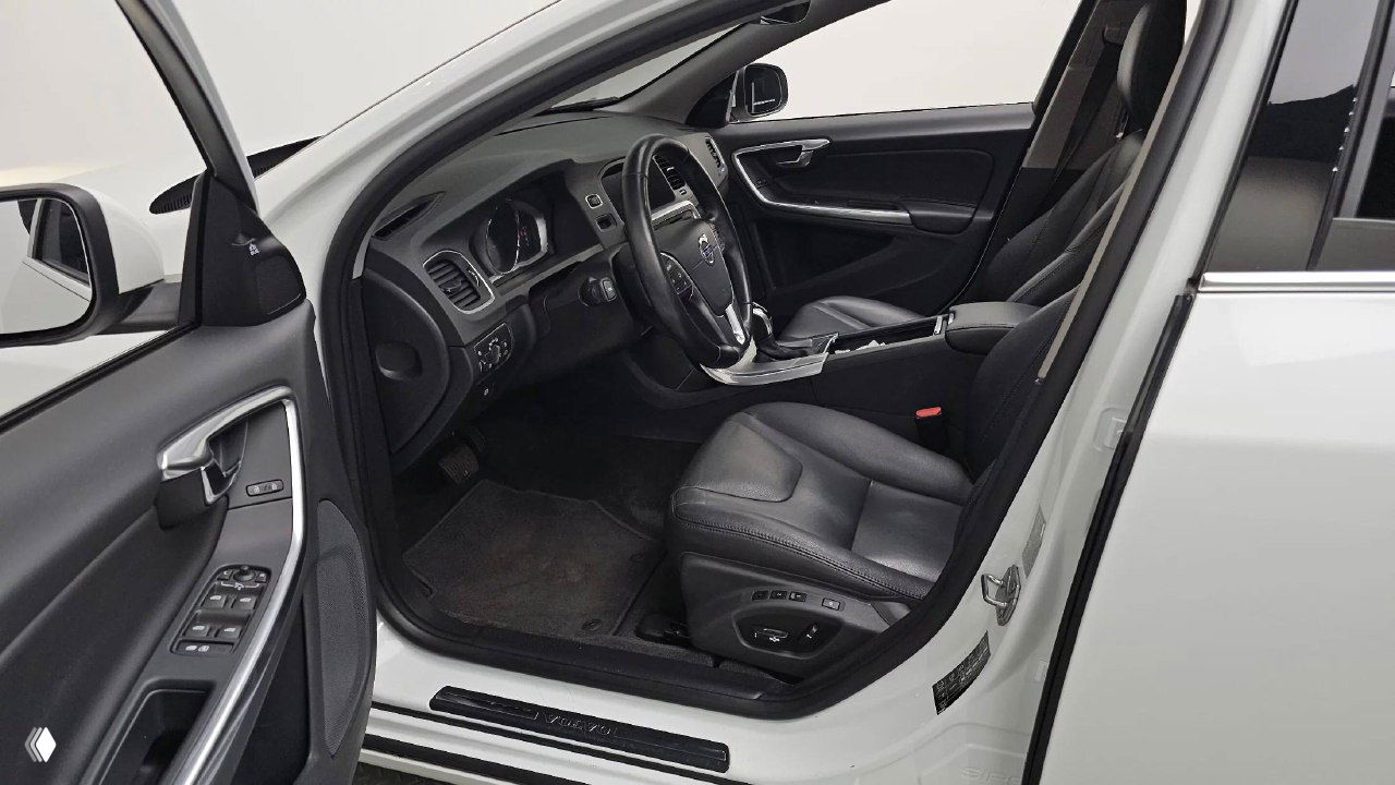 Вид через открытую переднюю левую дверь на салон Volvo S60: водительское место, кожаное сиденье и порог с накладкой.