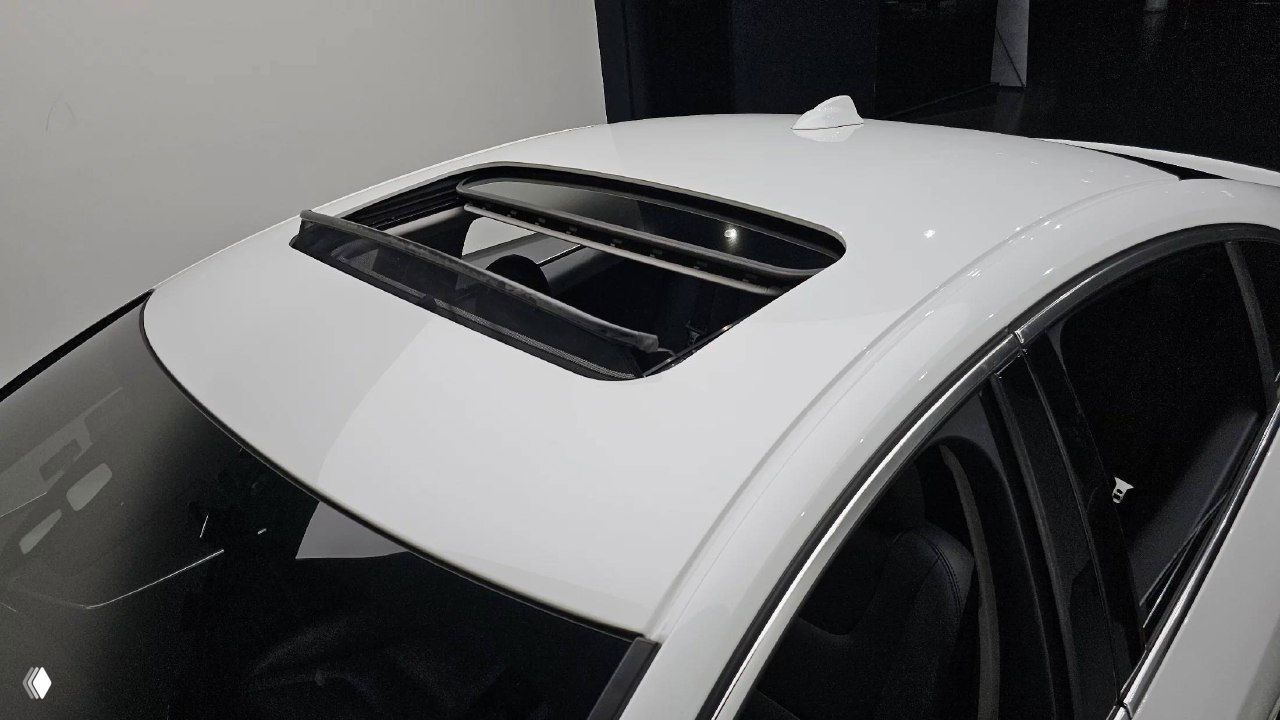 Откинутый панорамный люк на крыше белого Volvo S60, вид сверху показывает состояние крыши и люка автомобиля.