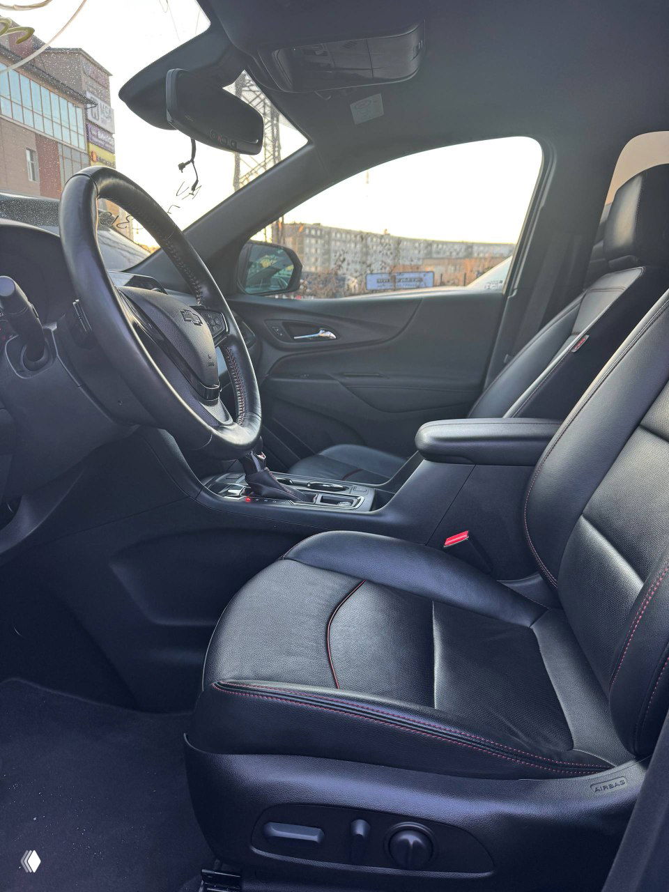 Интерьер передней части салона Chevrolet Equinox — профиль водительского сиденья, центральная консоль и пространство для ног; чёрная кожаная обивка с контрастной прострочкой.