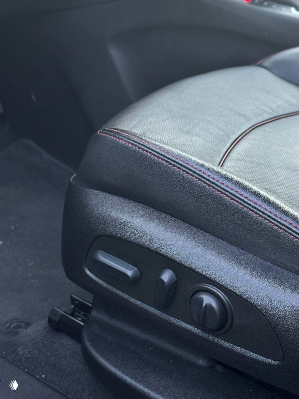 Крупный план блока регулировки сиденья в Chevrolet Equinox — кнопки и поворотные элементы для настройки положения, вид на кожу и отделочные швы сиденья.