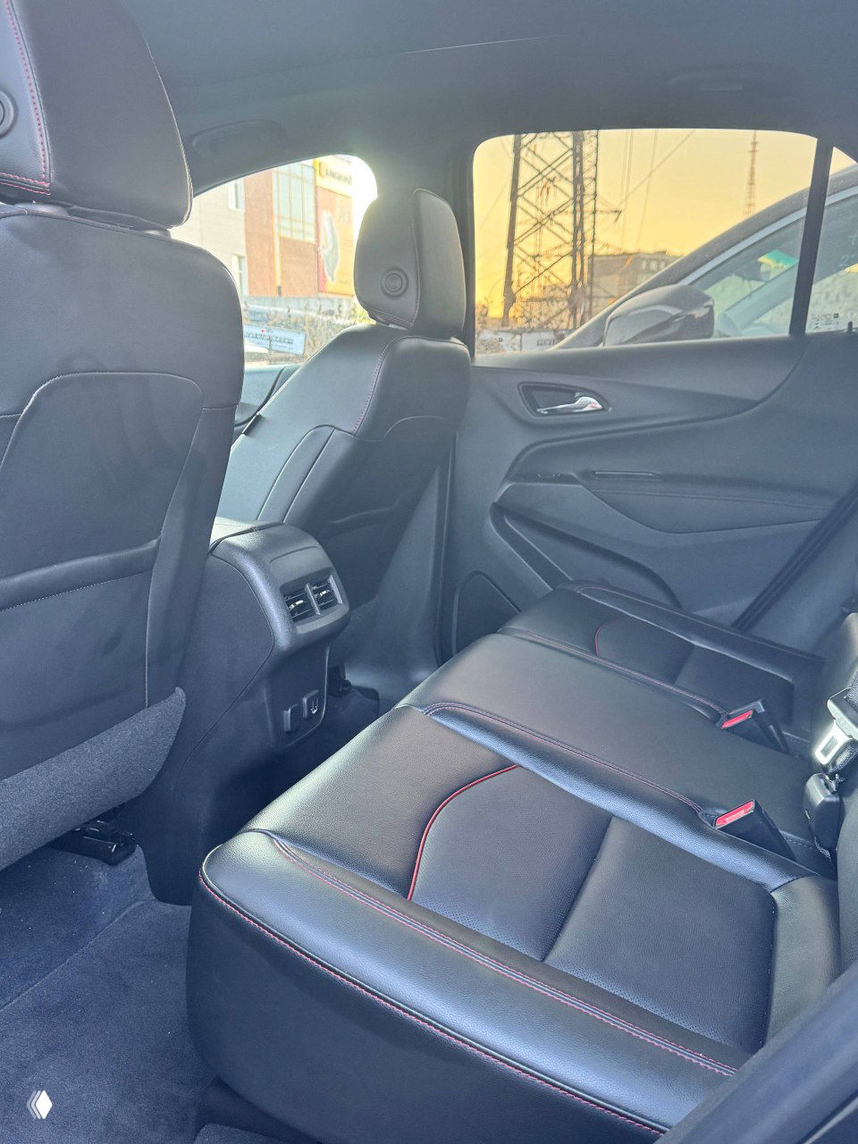 Задний диван Chevrolet Equinox — кожаная обивка, три посадочных места и воздуховоды для задних пассажиров; вид слева на пространство для ног и спинки передних сидений.