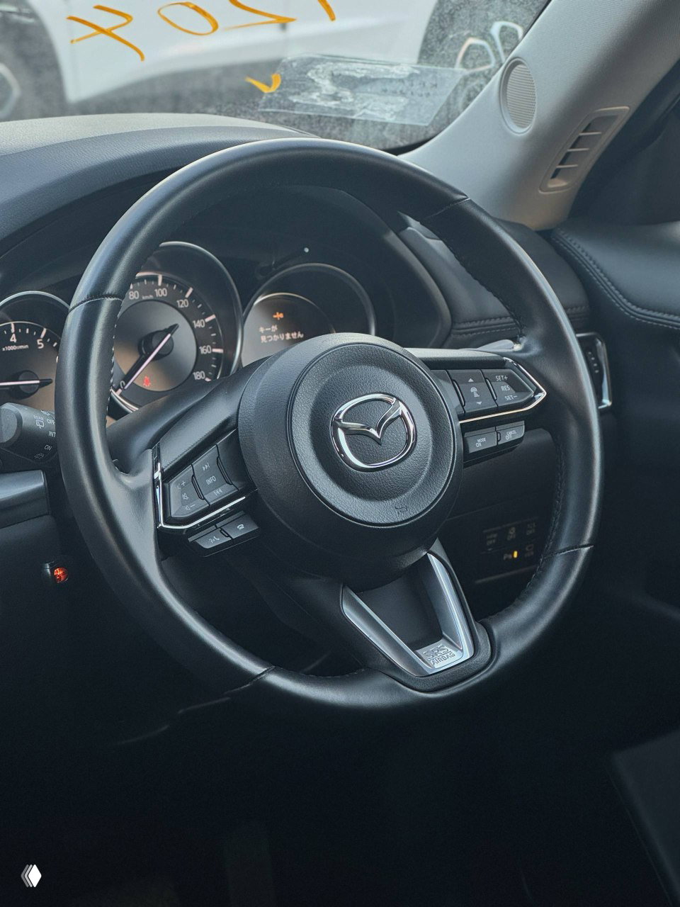 Рулевое колесо Mazda CX-5 с элементами управления аудио и круиз-контроля — вид салона со стороны водителя, состояние руля и панели приборов.