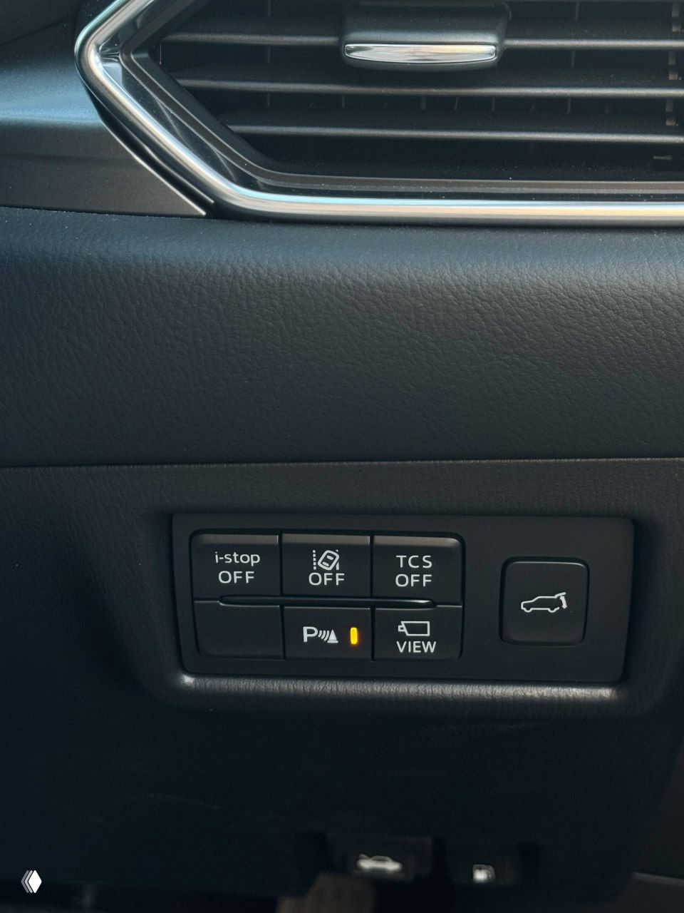 Панель с кнопками i-stop, TCS, парковочных ассистентов и кнопкой открывания крышки багажника в салоне Mazda CX-5 — вид вблизи, кнопки рабочие.