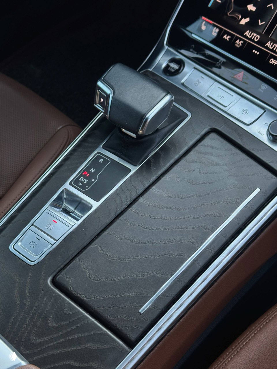 Ближний план селектора передач и центрального тоннеля Audi A6 с декоративной накладкой под дерево; состояние элементов интерьера видно подробно.