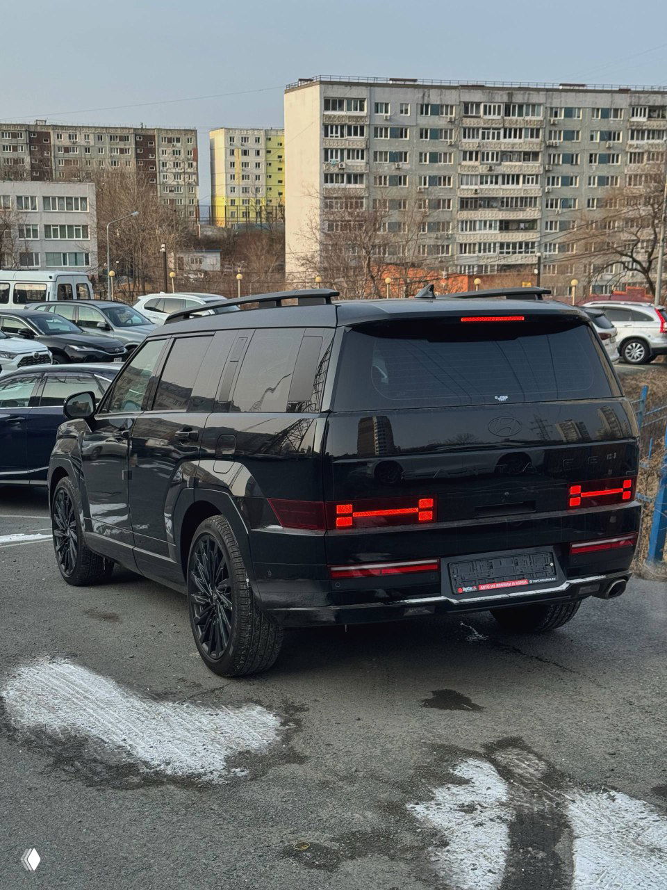 Задняя часть чёрного Hyundai Santa Fe Calligraphy на парковке: светодиодные фонари, багажник и задняя оптика в городском окружении