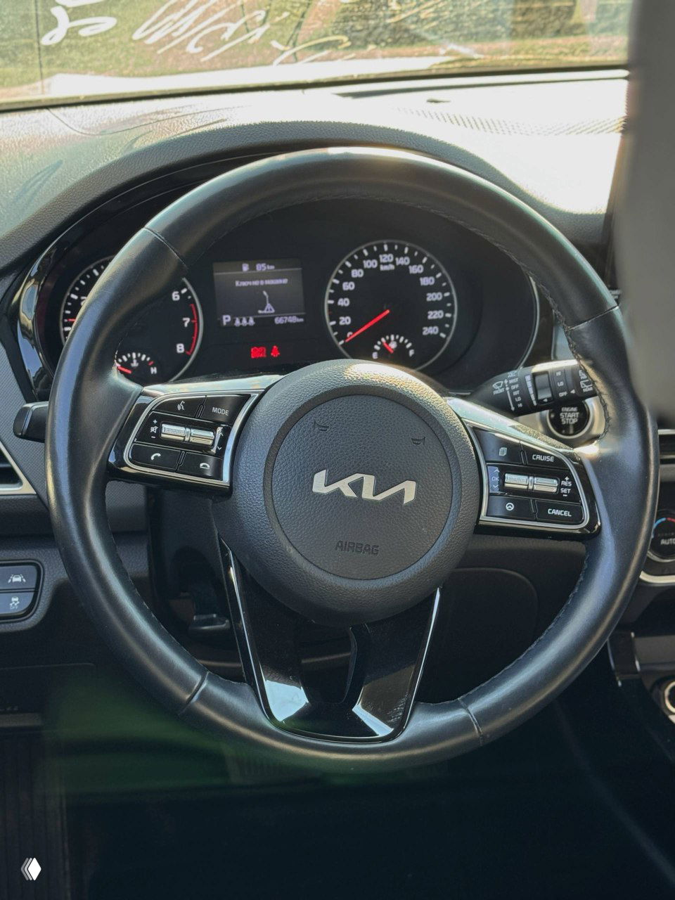 Кожаный руль KIA Seltos — крупный план рулевого колеса с логотипом KIA и органами управления мультимедиа и круиз-контроля
