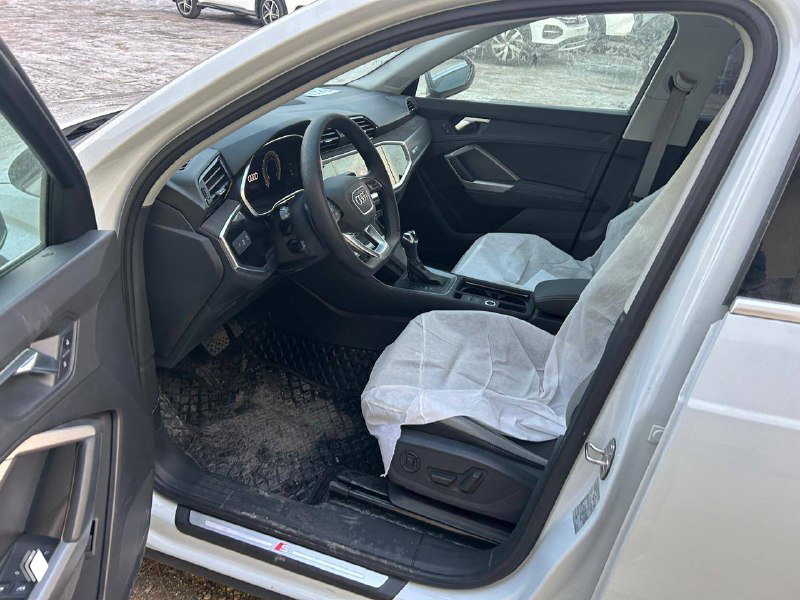 Интерьер Audi Q3: вид водительского места, рулевое колесо, приборная панель и защитная накидка на сиденье на момент осмотра в Уссурийске