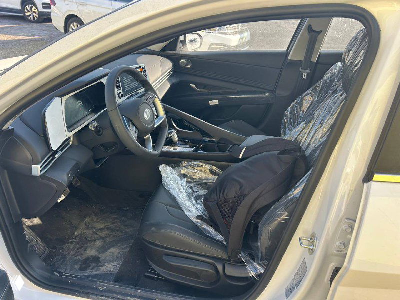 Интерьер Hyundai Elantra: передние сиденья, руль и центральная консоль, защитные чехлы на пассажирском месте при приемке