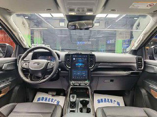 Салон Ford Ranger: панель приборов, руль, большой вертикальный сенсорный экран мультимедиа и передние сиденья в чёрной отделке внутри автомобиля.