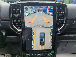 Крупный план дисплея с видом камер 360 градусов на Ford Ranger: изображение парковки сверху и задней камеры, интерфейс помощи при маневрировании.