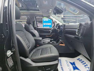 Передние кресла Ford Ranger 2024 года: чёрная обшивка, боковая поддержка и общий вид кабины со стороны пассажира в выставочном зале.