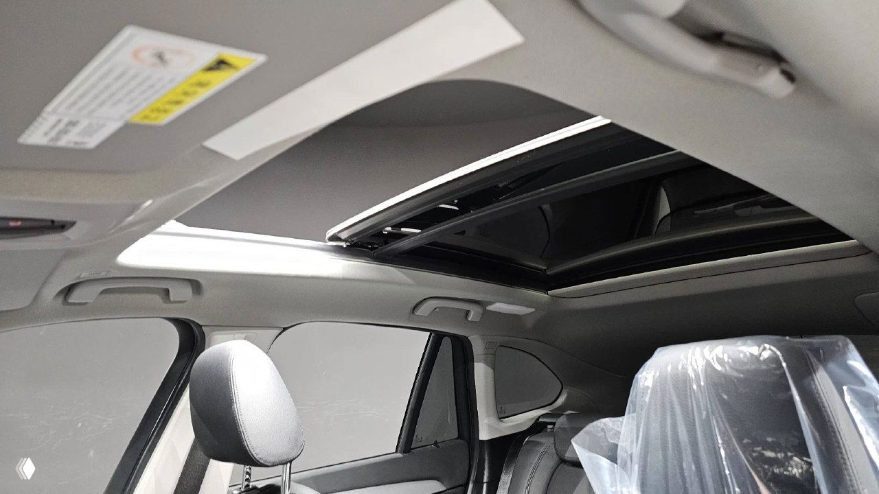 Открытый панорамный люк (sunroof) в салоне BMW X1, вид на крышу и верхнюю часть интерьера с подсветкой и механизмом люка.