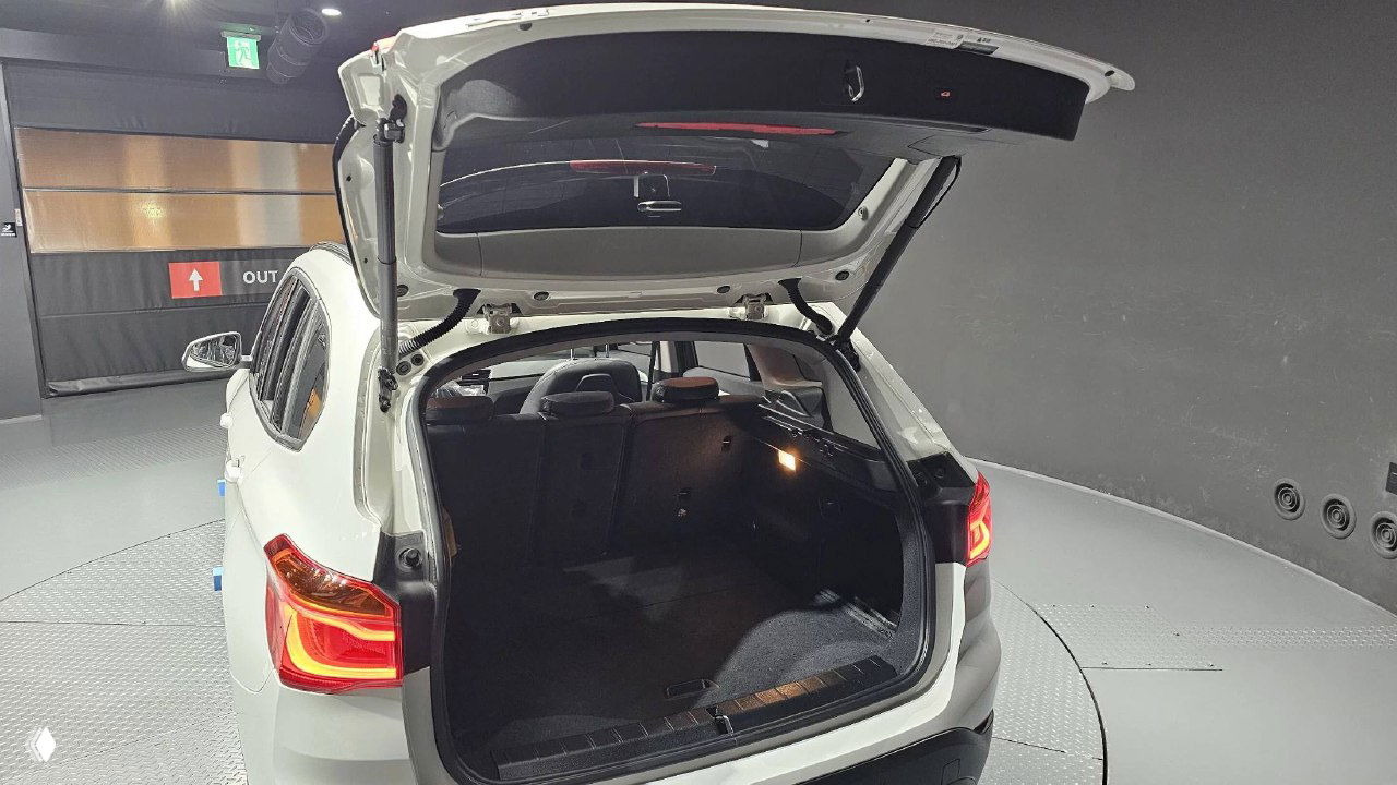 Открытый багажник BMW X1 с освещением, видно грузаовое пространство, состояние обивки багажного отделения и заднюю дверь поднятой вверх.