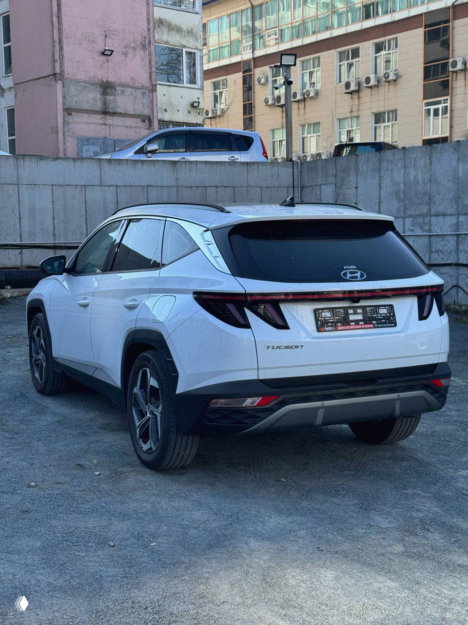 Hyundai Tucson 2020 белого цвета, вид сзади-справа на городской парковке, видна кормовая светодиодная оптика и номерная табличка.