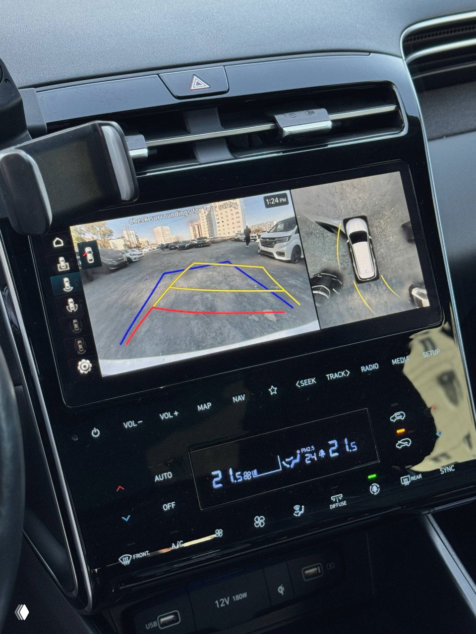 Центральная мультимедийная панель Hyundai Tucson: экран с камерой заднего вида и разметкой парковки, органы управления внизу.