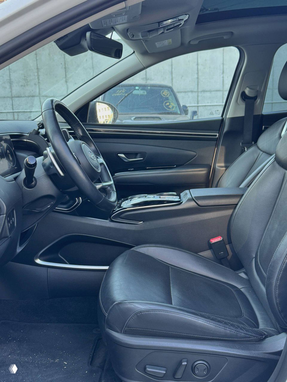 Вид на переднее пассажирское сиденье и центральный тоннель Hyundai Tucson: кожаная обивка, подстаканник и элементы управления.