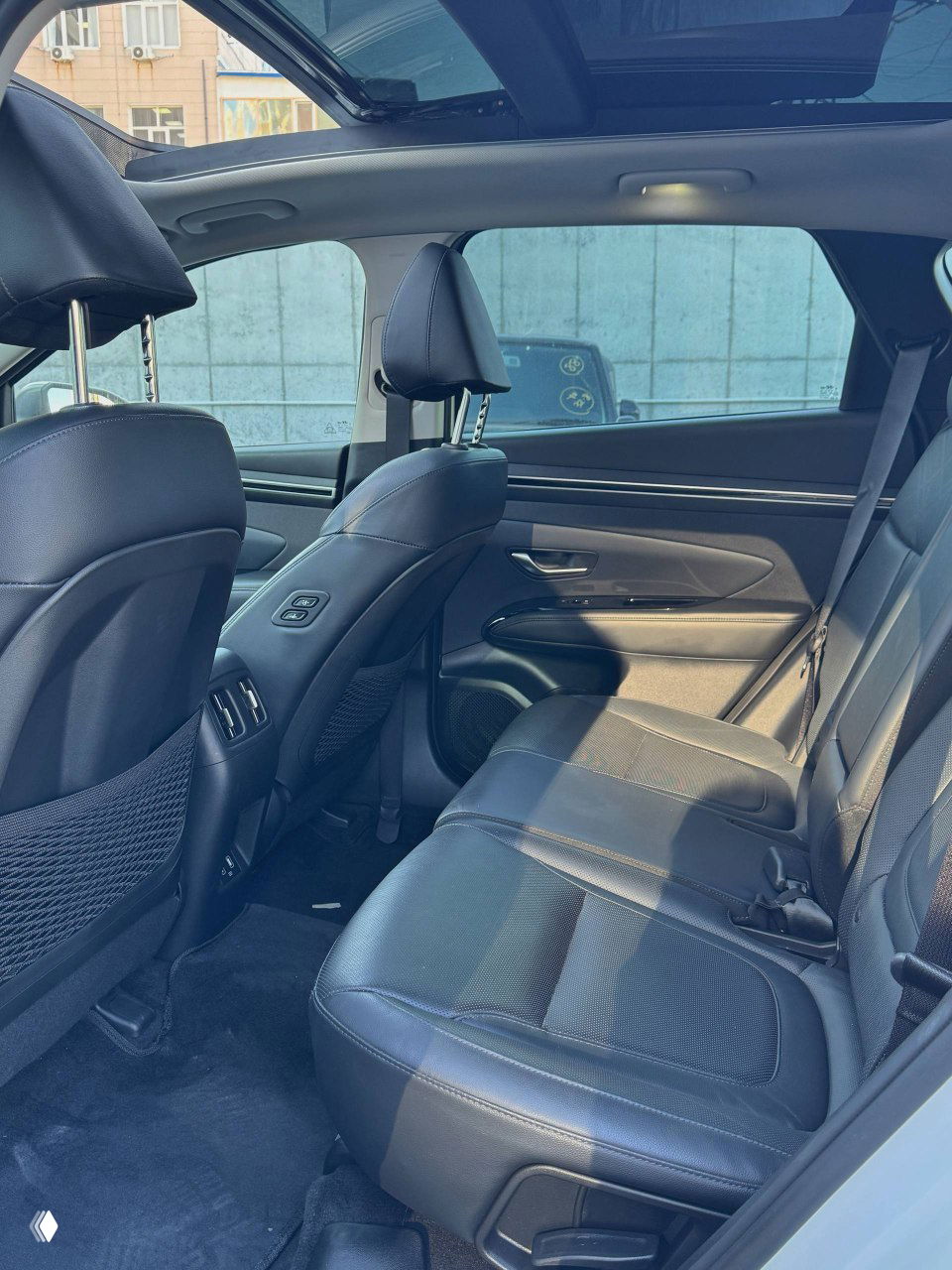 Задний ряд сидений Hyundai Tucson, фото показывает кожаную обивку, пространство для ног и панорамную секцию крыши сверху.