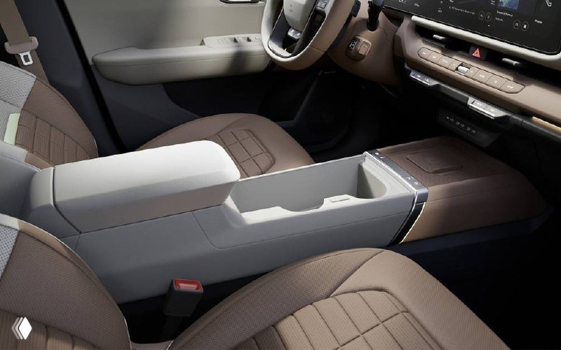 Внутренний вид салона KIA Seltos, центральный подлокотник и передние сиденья с отделкой, видна практичная компоновка пространства для хранения.